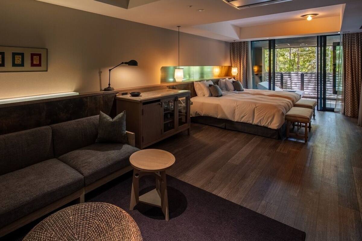Una habitación de hotel con sofá, cama, una mesita y vistas al exterior.