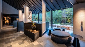 A modern interior with a reception desk, seating area, and large windows overlooking a garden. - Fufu Nara (Nara)