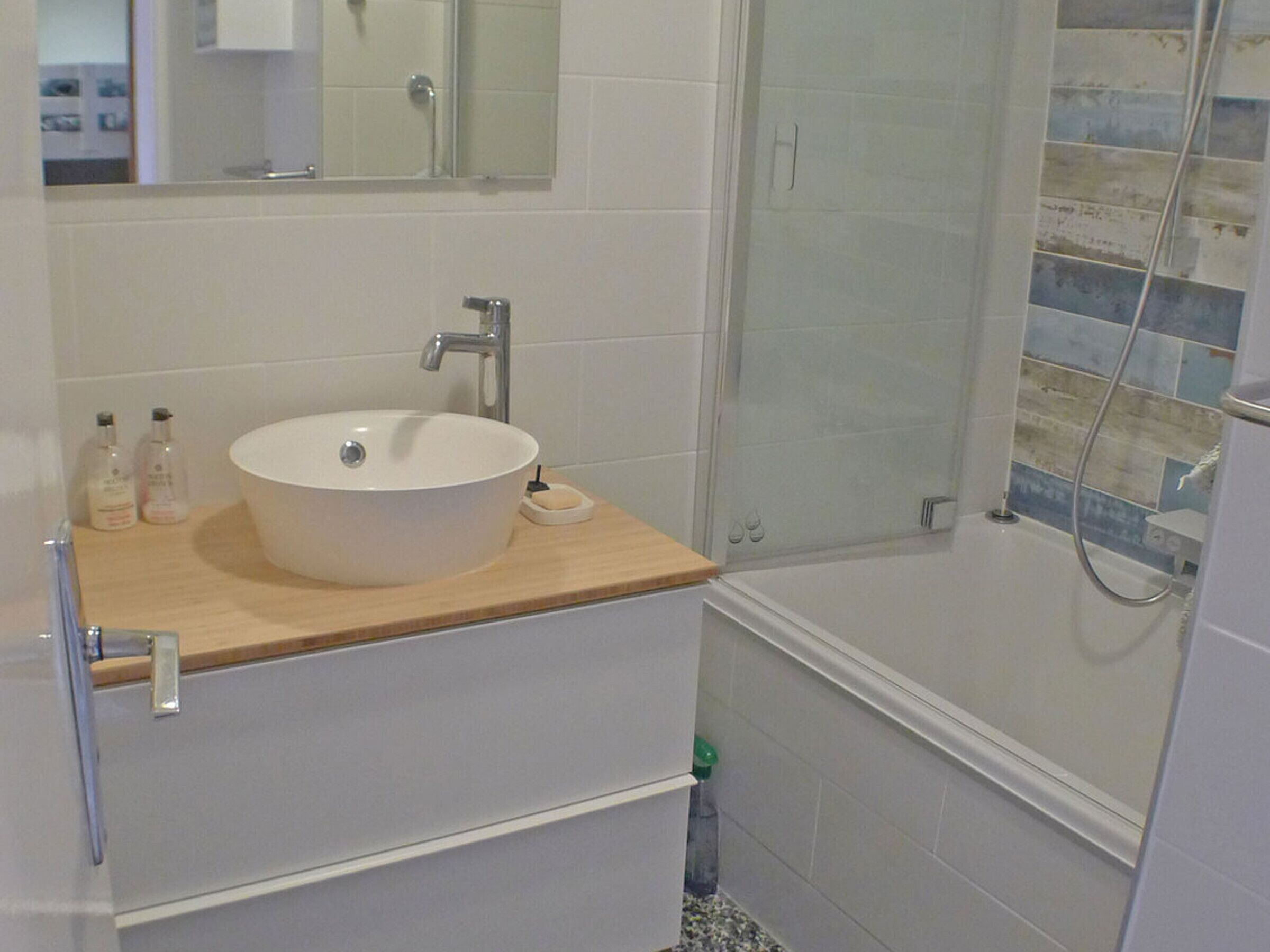 A bathroom with a white sink, a mirror, and a shower area.