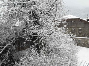 A rustic barn with a snow-covered roof, surrounded by dense, snow-laden trees. - Bright studio for 4, pets allowed, wifi included, central Samoëns (Samoëns)