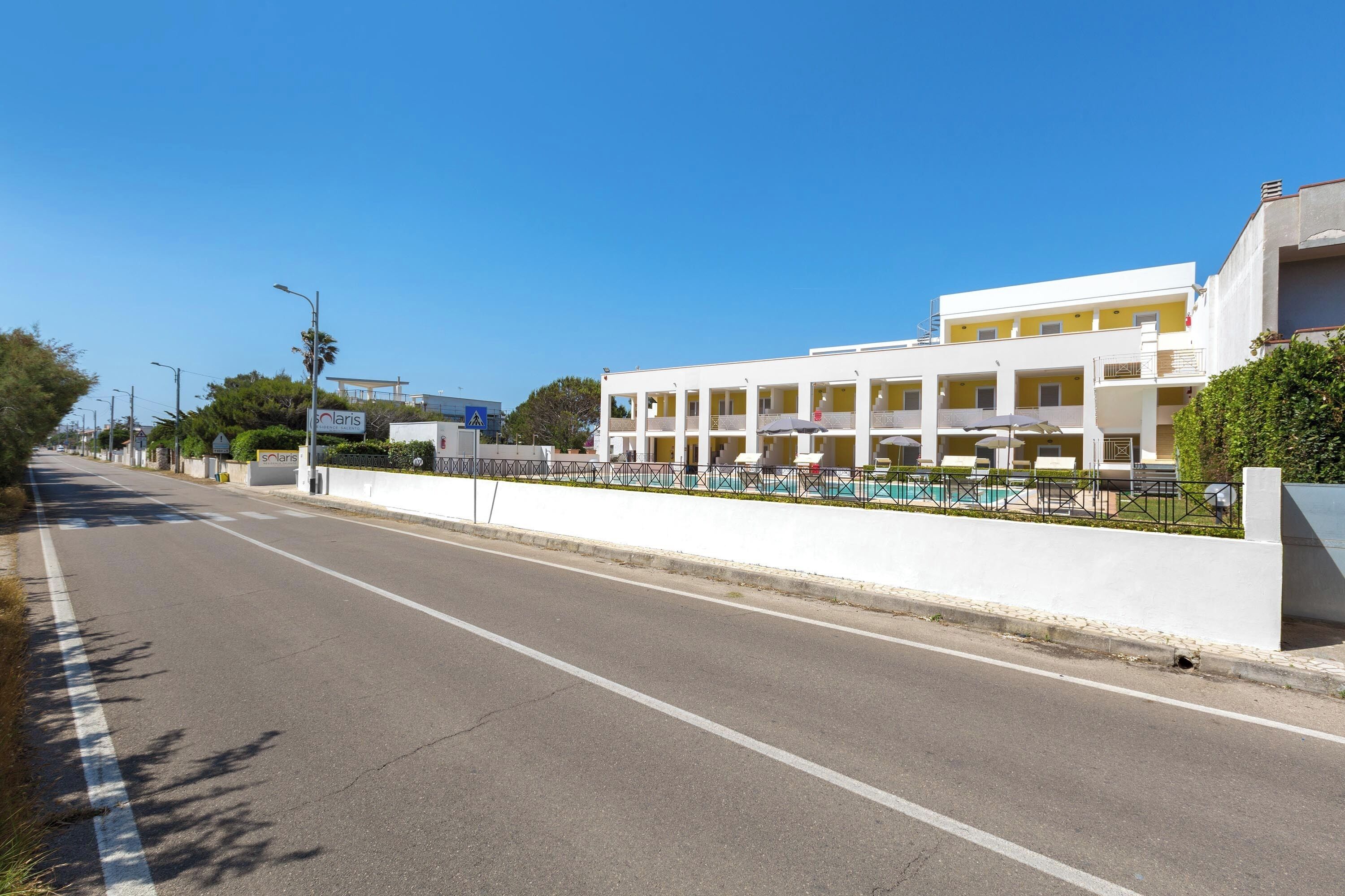 Un hôtel à plusieurs étages, doté d’une façade blanche, de balcons et d’un espace piscine.