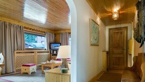 Une pièce chaleureuse avec un plancher en bois, une télévision, un banc en bois et une porte.
