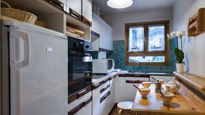 Une cuisine compacte équipée d’un réfrigérateur, d’un four, d’un four à micro-ondes et d’un plan de travail en bois.