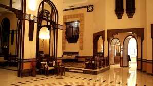 A lobby with a checkered floor, wooden furniture, and arched doorways. - Faraana Reef - All-inclusive (Sharm El Sheikh)