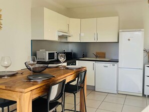 Une cuisine compacte avec des meubles blancs, un four à micro-ondes, un grille-pain et un réfrigérateur.
