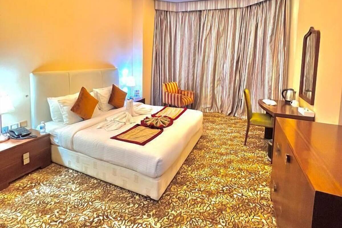 Habitación de hotel con una cama grande, un escritorio, una silla y una alfombra estampada.