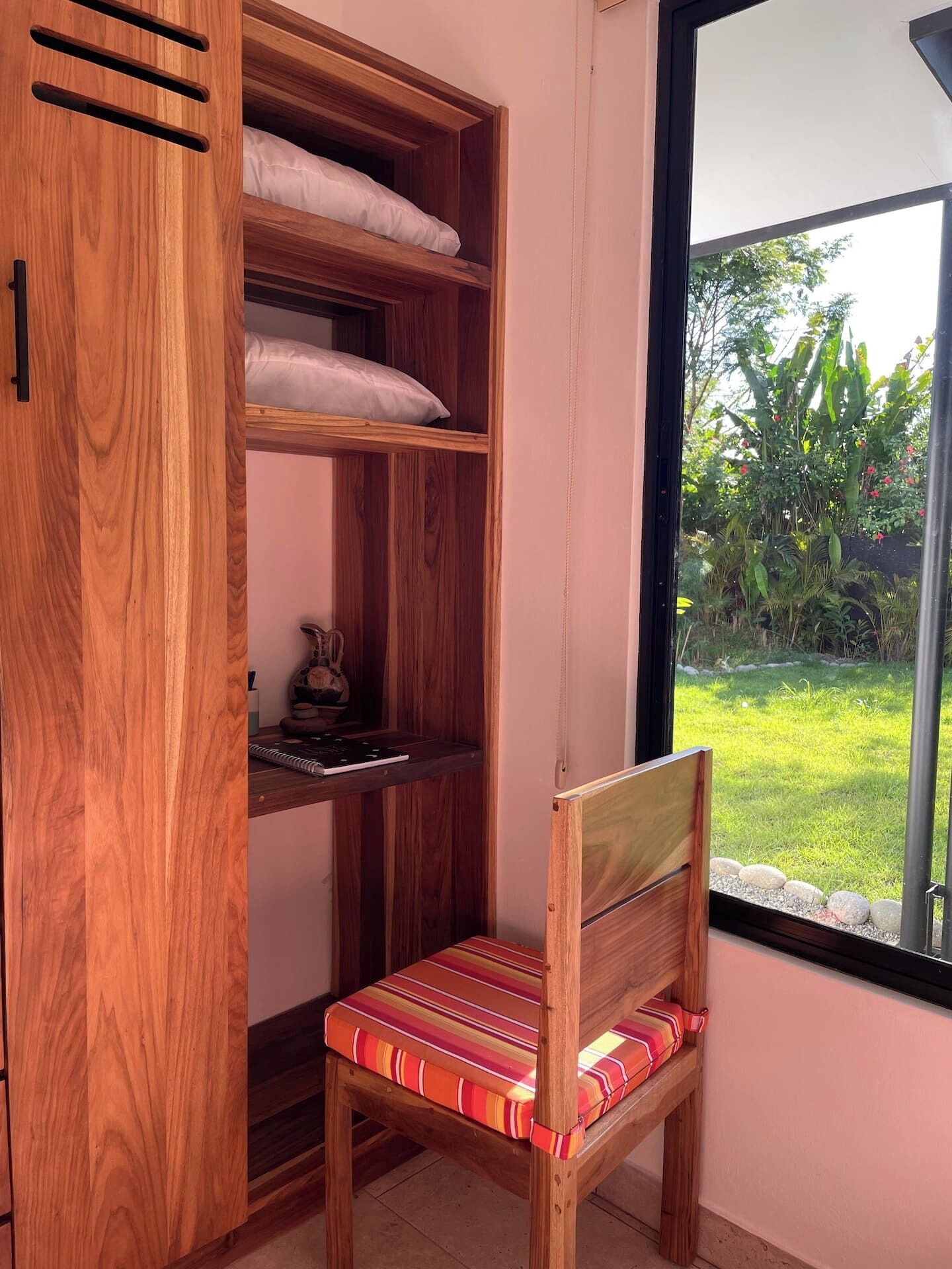 Ett träskåp med hyllor och en stol med en randig kudde.