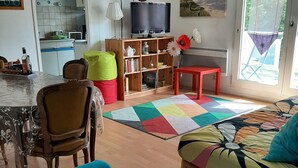 Ein Wohnzimmer mit einer Couch, einem Sessel, einem kleinen Tisch und einem Bücherregal.