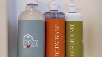Three bottles of liquid soap on a white shelf.