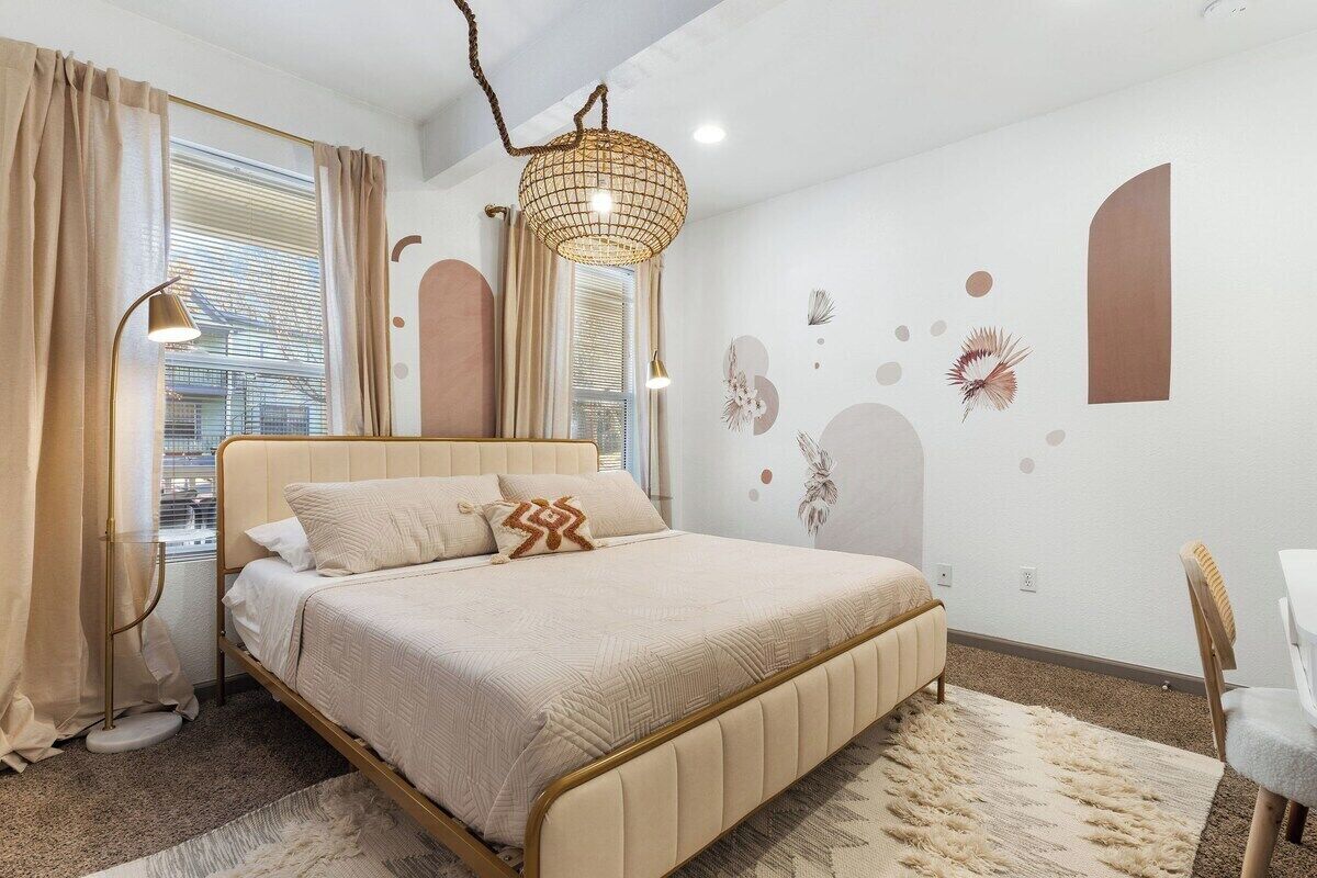 A bedroom with a bed, bedside lamps, a desk, and a chair.