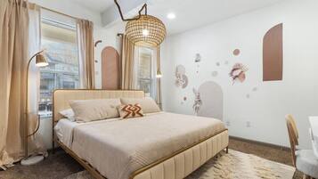 A bedroom with a bed, bedside lamps, a desk, and a chair.