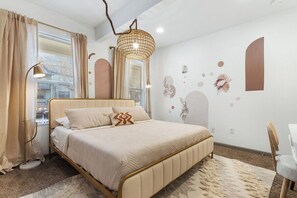 Ein Schlafzimmer mit einem Bett, Nachttischlampen, einem Schreibtisch und einem Stuhl.