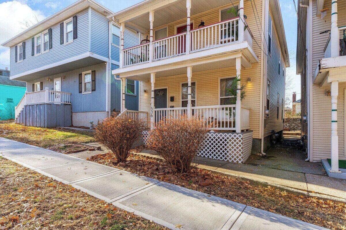 A two-story residential building with a front porch and a covered front entrance.