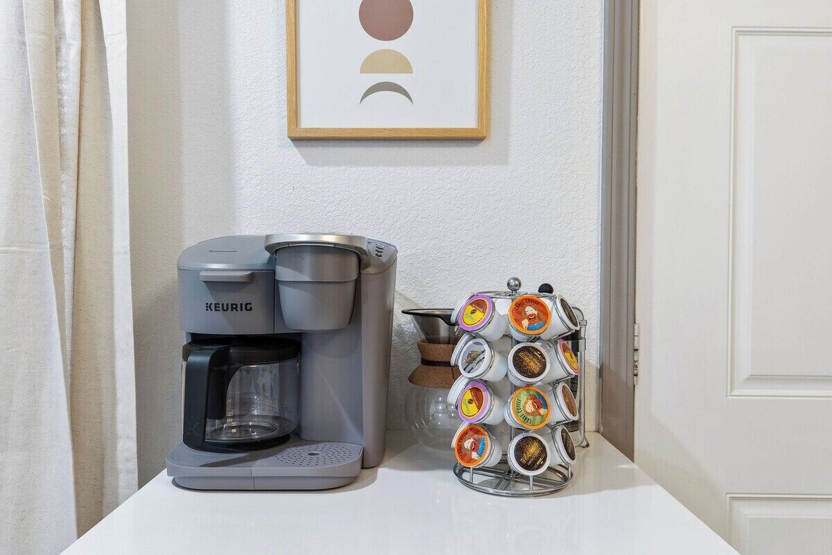 A Keurig coffee maker and a coffee pod holder on a white countertop.