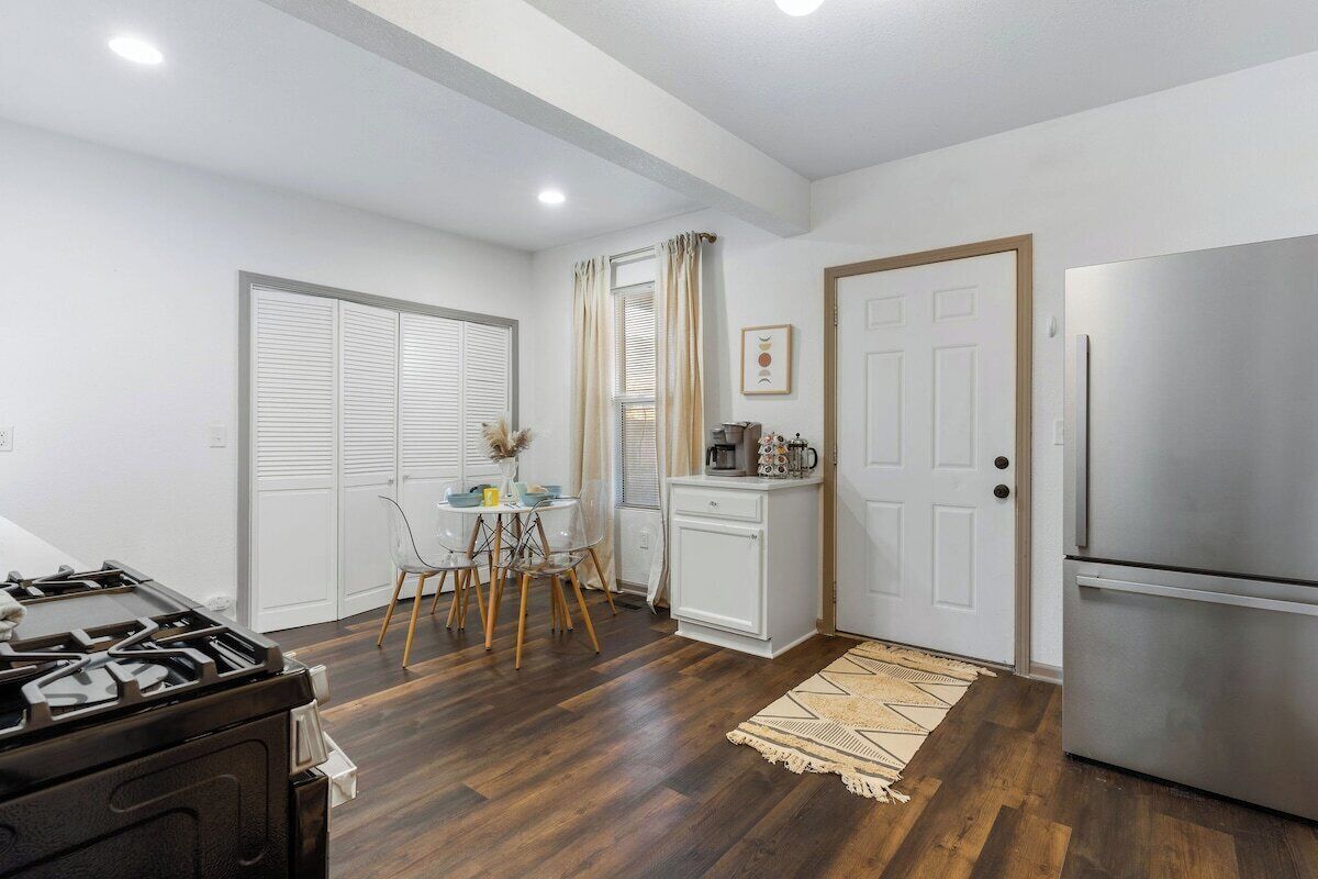 A compact kitchen with a gas stove, a refrigerator, and a dining area with a table and chairs.