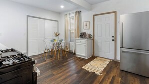 A compact kitchen with a gas stove, a refrigerator, and a dining area with a table and chairs.