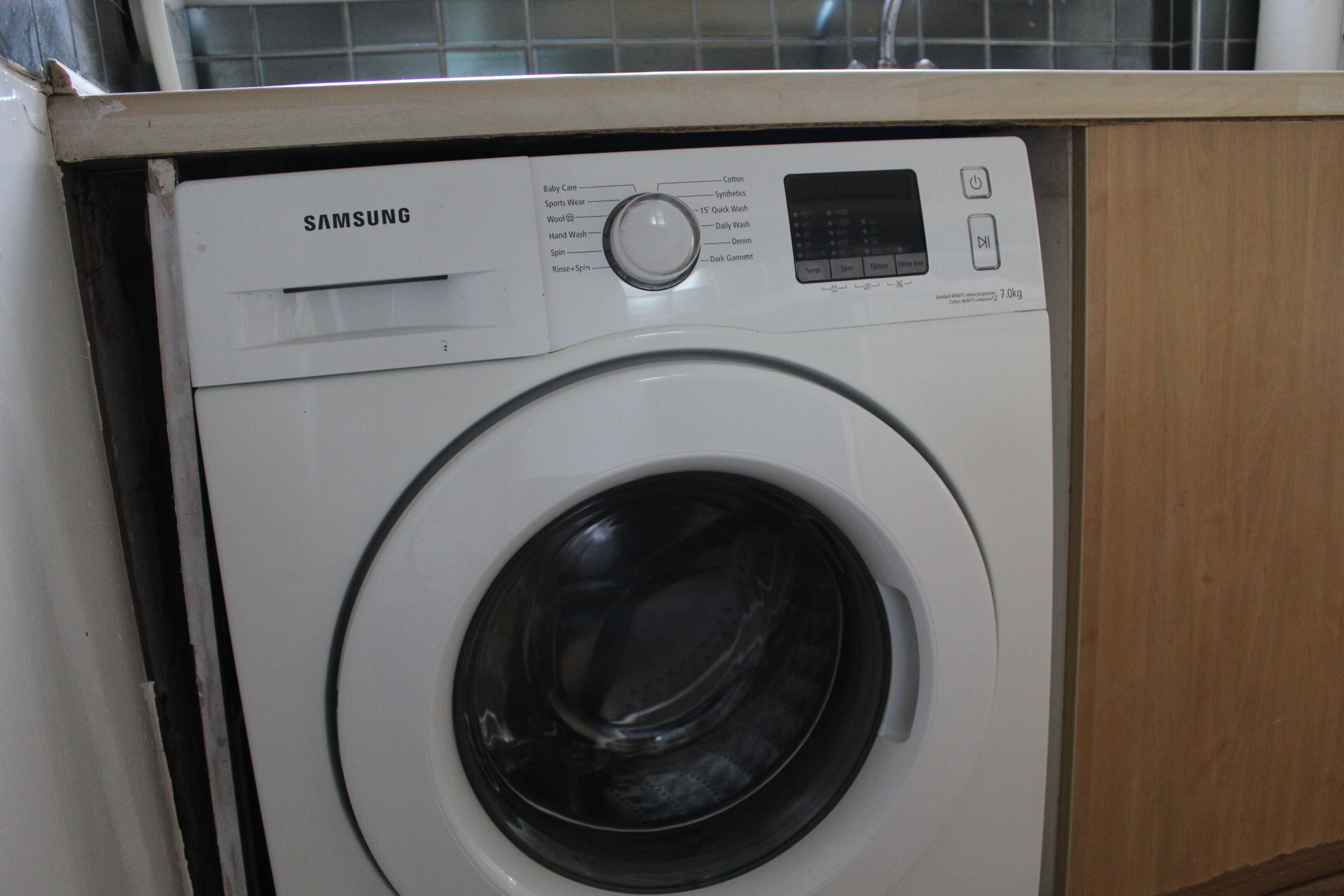 Une machine à laver Samsung dotée d’un panneau de commande et d’une porte à chargement frontal.