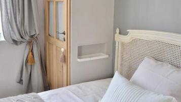 Un dormitorio con una cama, un armario de madera, una estantería en la pared y una ventana con cortinas.