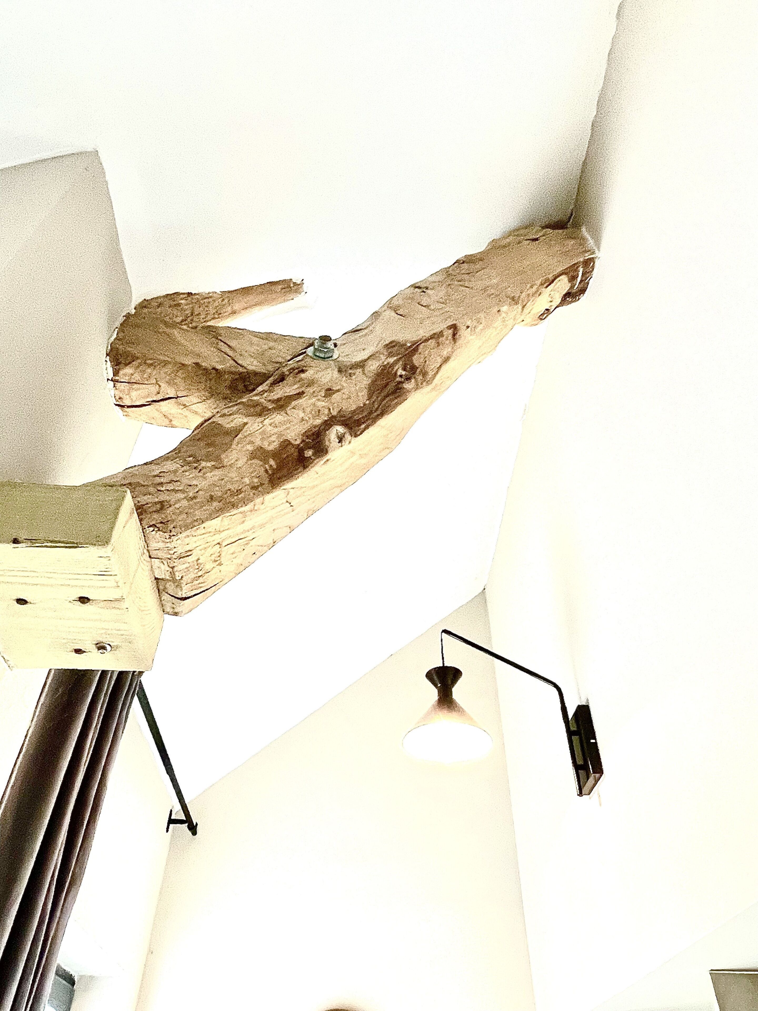Una escultura de madera con una lámpara en una habitación.