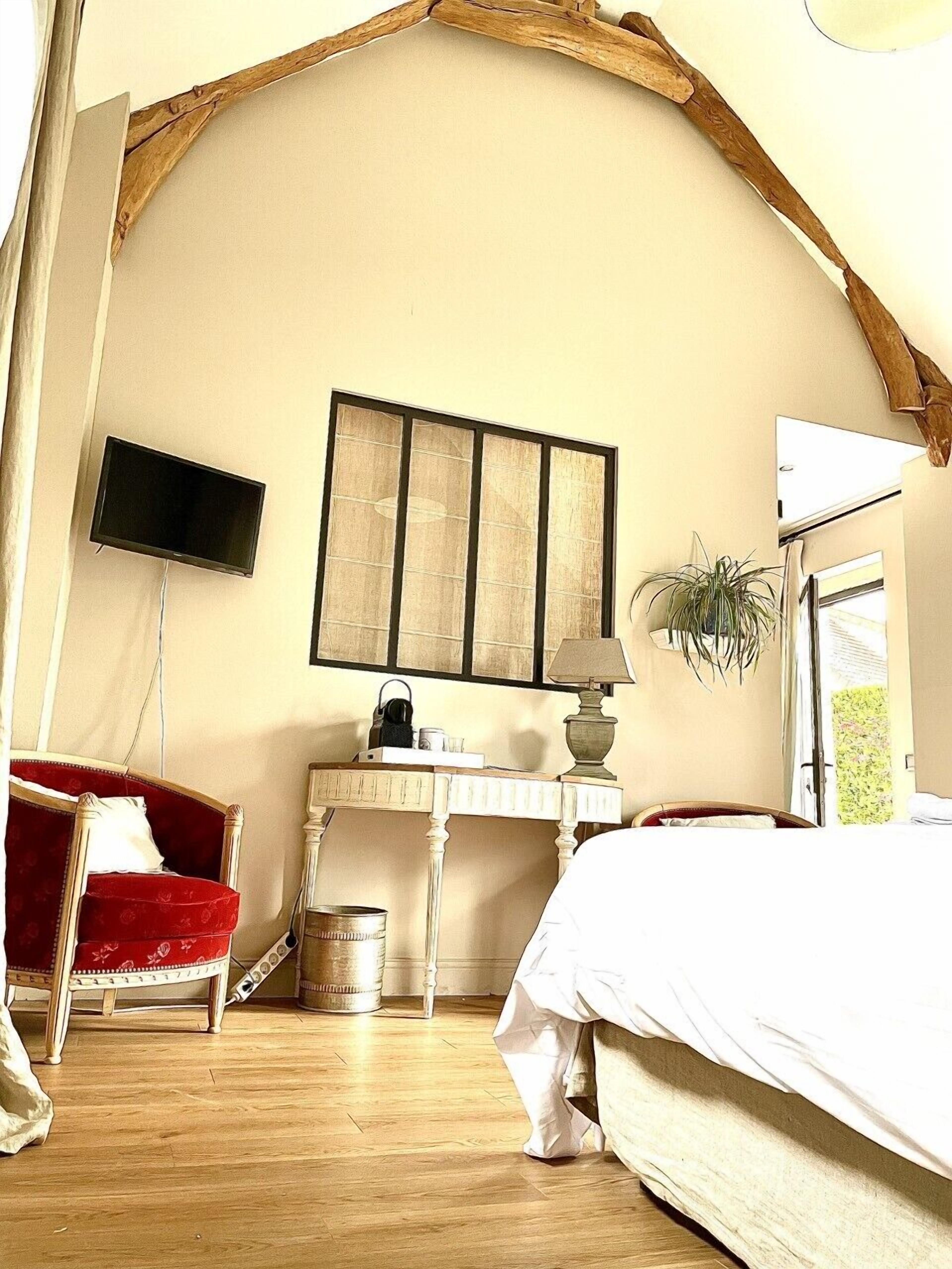 Een slaapkamer met een bed, een bureau, een stoel, een televisie en een raam.