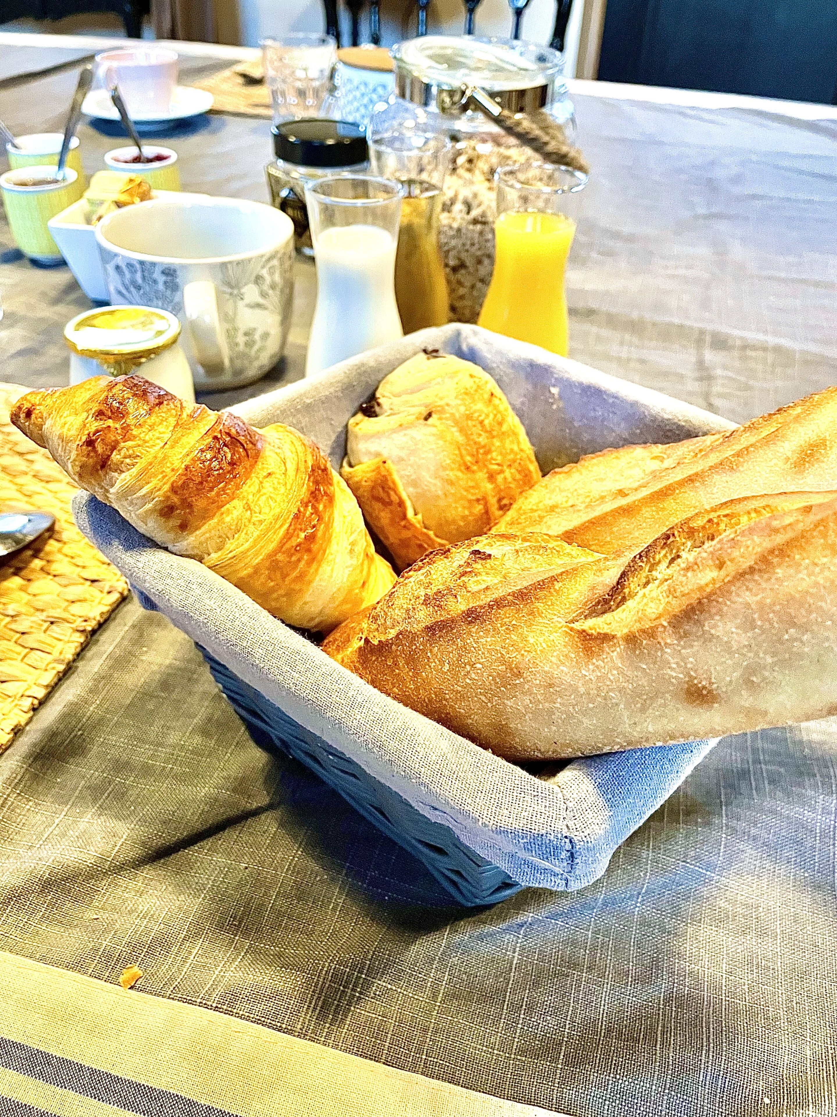 A tray of croissants and bread on a table with various breakfast items.