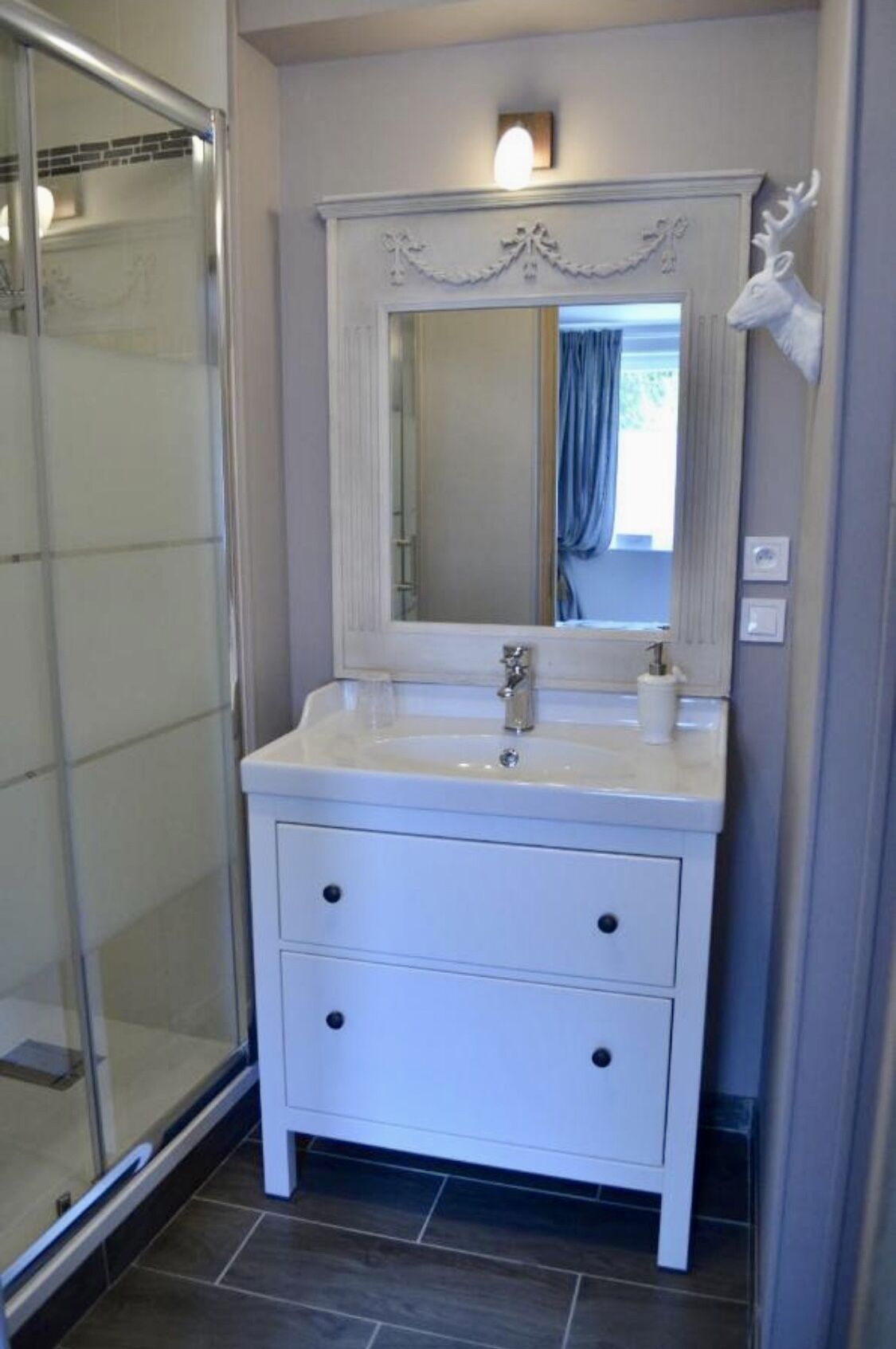 A bathroom with a white vanity, a large mirror, and a shower area.