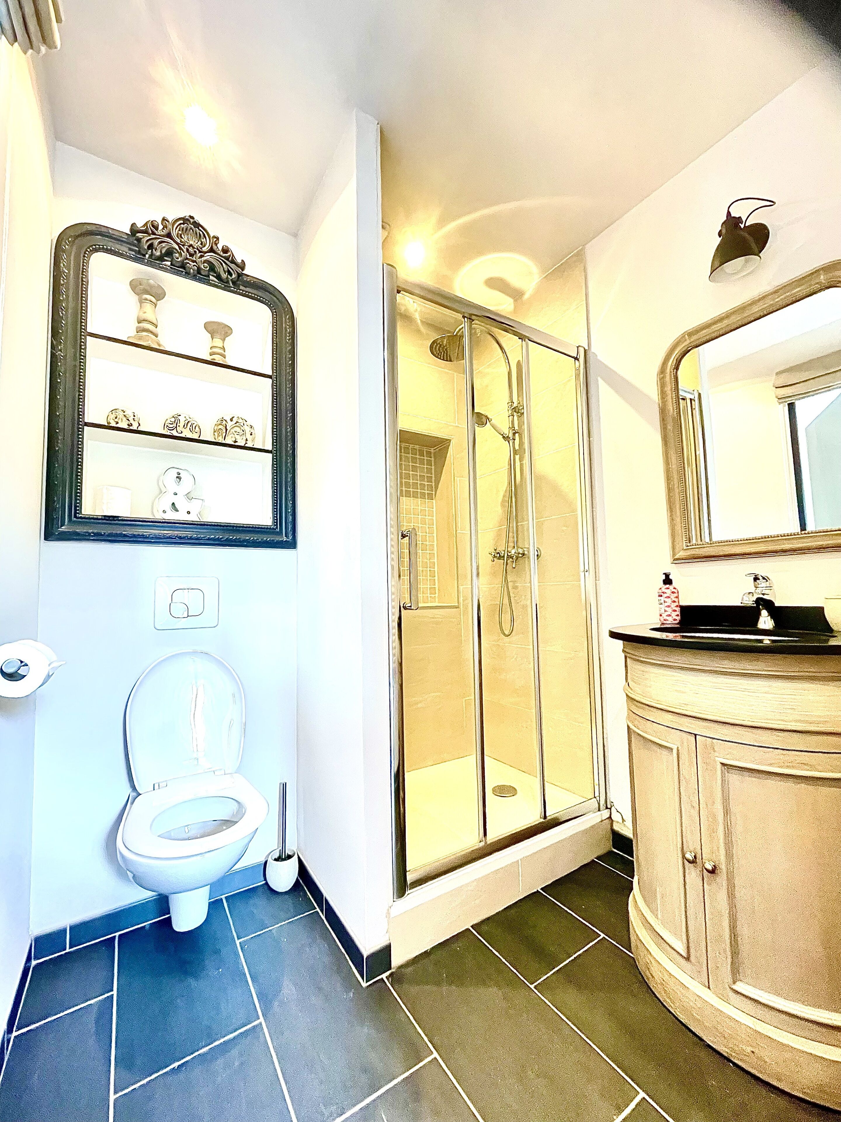 Un baño con inodoro, ducha, lavabo y espejo.