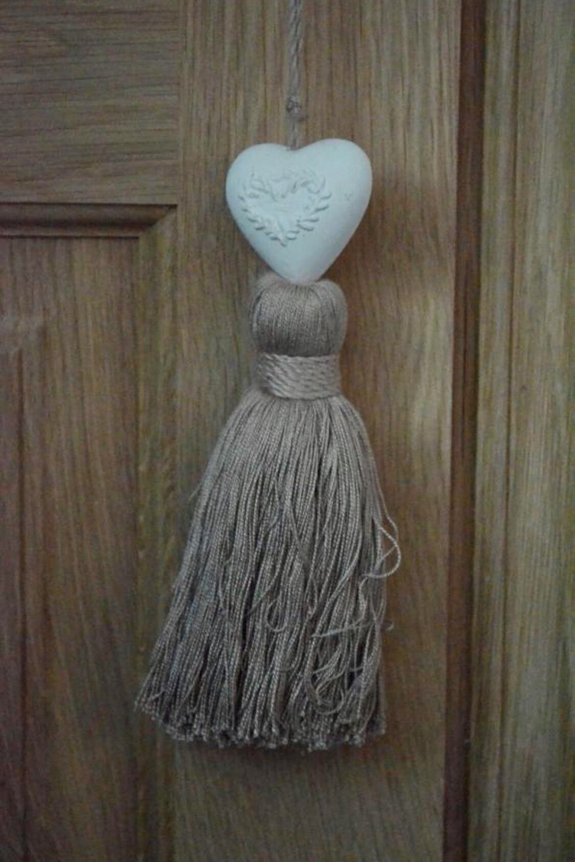 Una decoración en forma de corazón con un fleco colgando de una puerta de madera.
