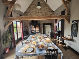 Un comedor con mantel a cuadros, vigas de madera, paredes de ladrillo y una pizarra con el menú.