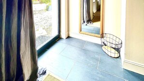 A room with a large window, a mirror, and a small wire basket on the floor. - Le Paddock (La Drenne)