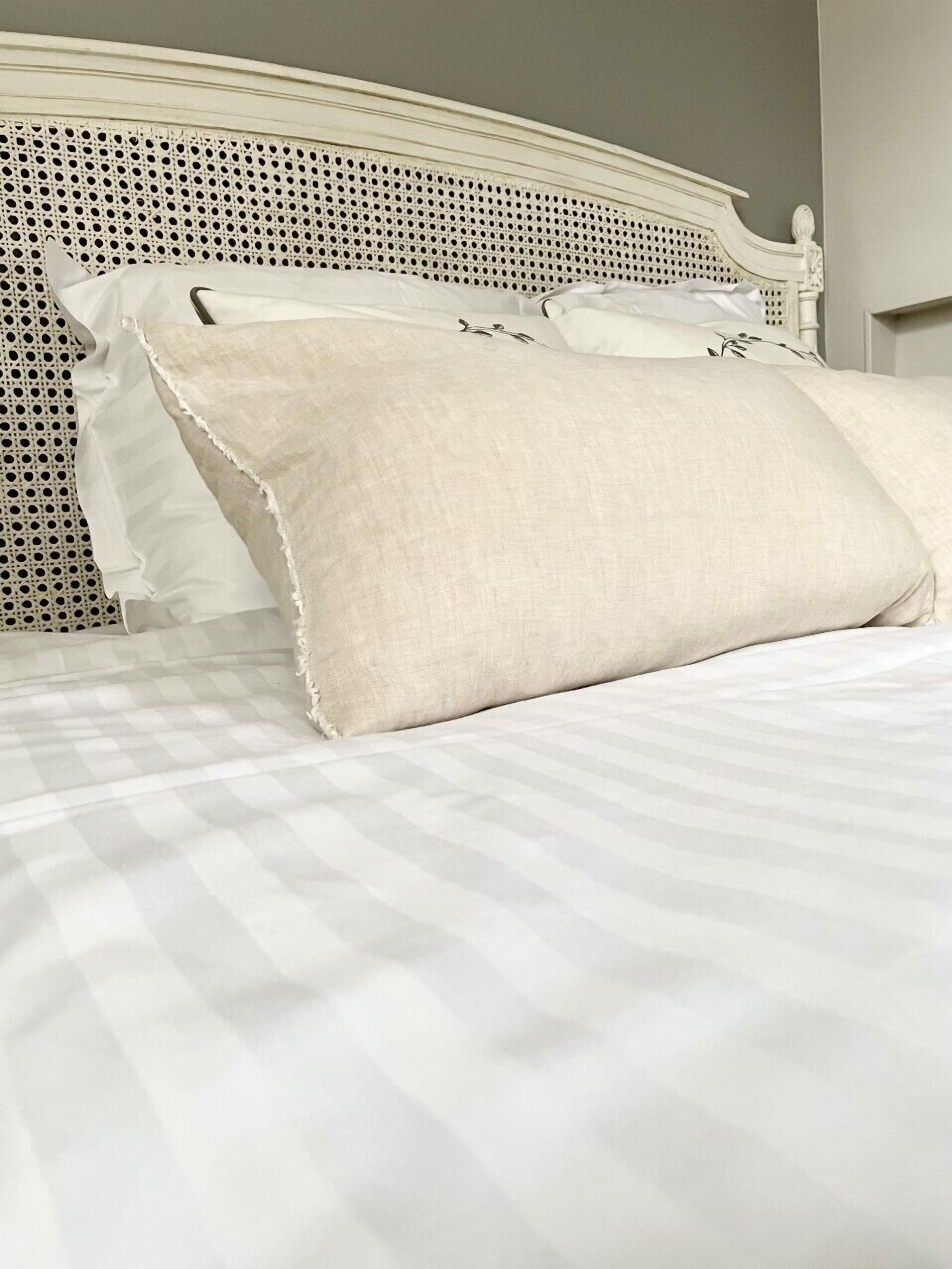 Una cama con cabecera blanca y colcha a cuadros.