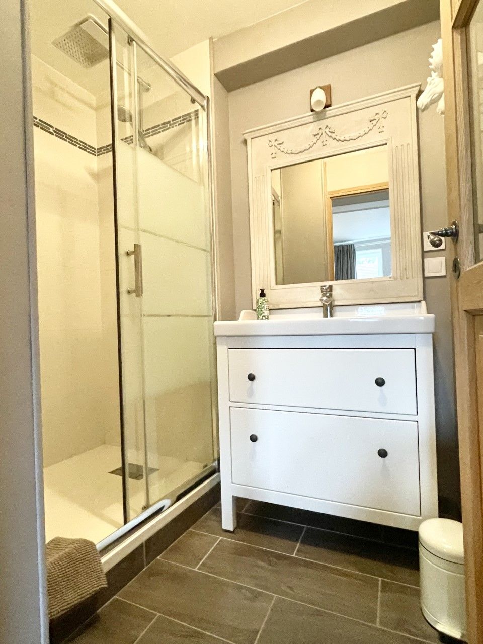 Un bagno con box doccia in vetro, un mobile lavabo bianco con specchio e un water.