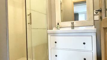 Un bagno con box doccia in vetro, un mobile lavabo bianco con specchio e un water.