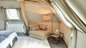 A cozy attic bedroom with a sofa, a small table, and a lamp. - Le Paddock (La Drenne)