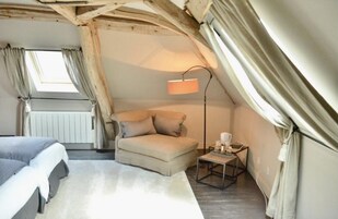 Un dormitorio acogedor en el ático con un sofá, una mesita y una lámpara.
