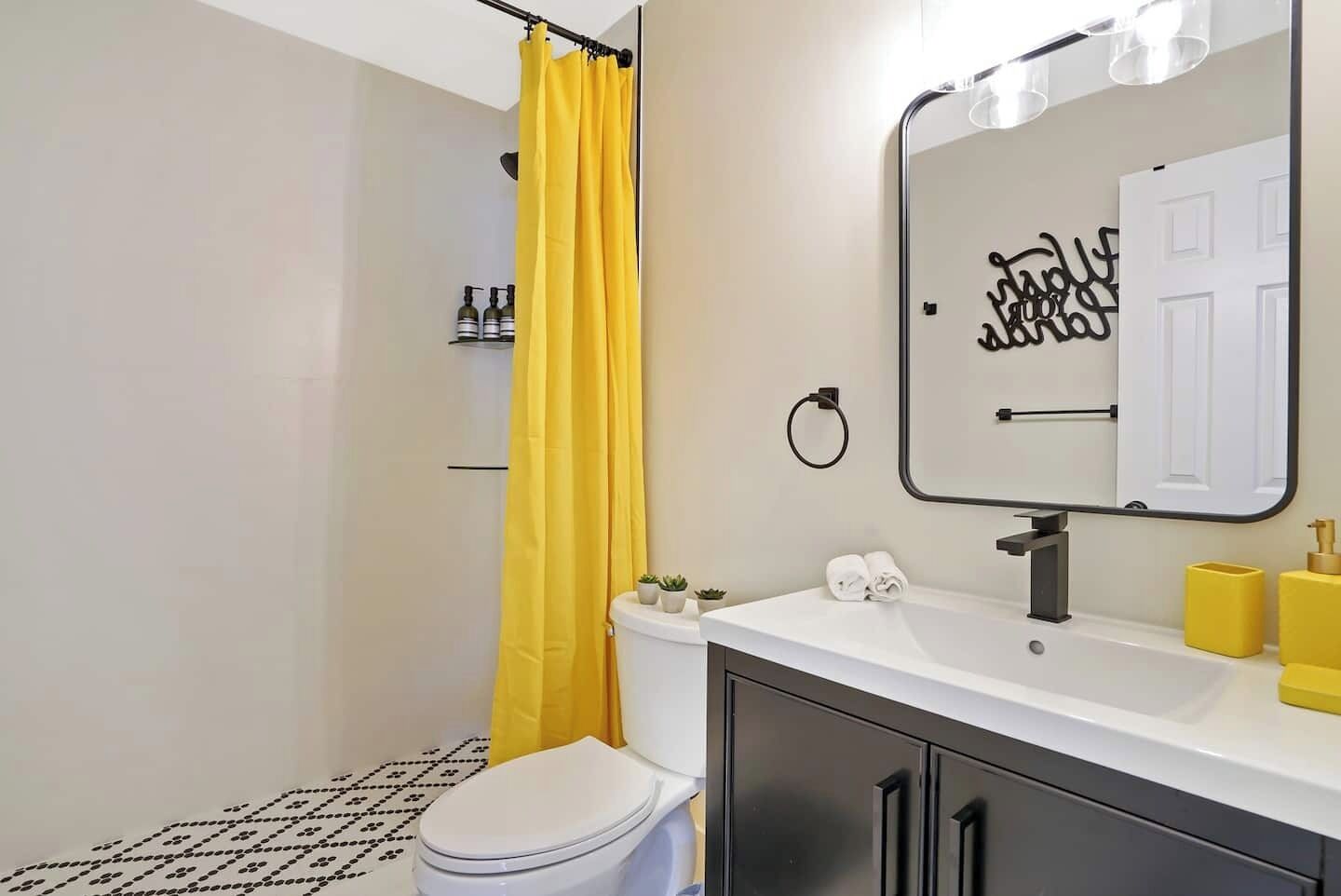 A bathroom with a toilet, a sink with a mirror, a shower curtain, and a toilet paper holder.