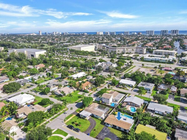 An aerial view of a residential area with houses, roads, and a large building with a swimming pool.