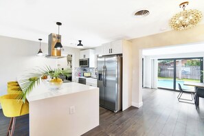A modern kitchen with a central island, stainless steel appliances, and a view of a backyard with a pool.