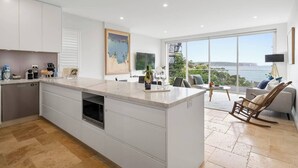 Una cocina moderna con una isla grande, armarios blancos y vistas al mar.