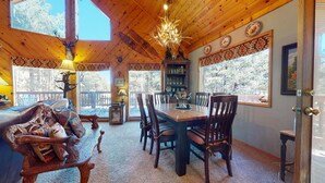 Un coin repas en bois avec une grande table et des chaises, un lustre et une bibliothèque.
