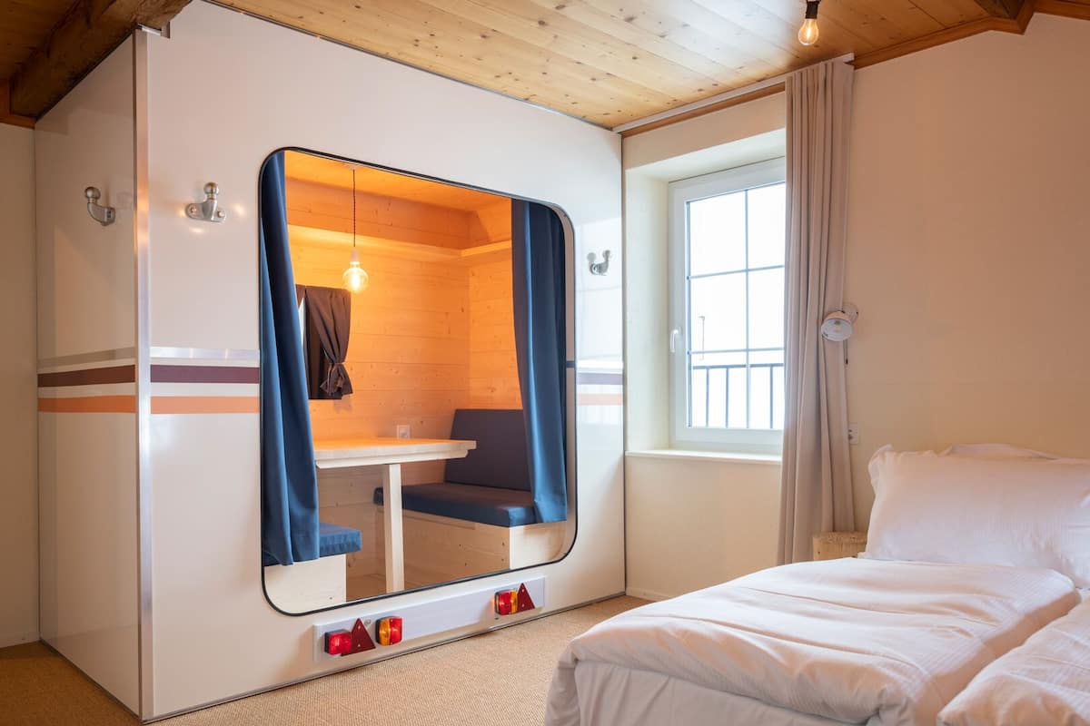 A compact room with a bed, a small table, and a seating area with a view of the outside.