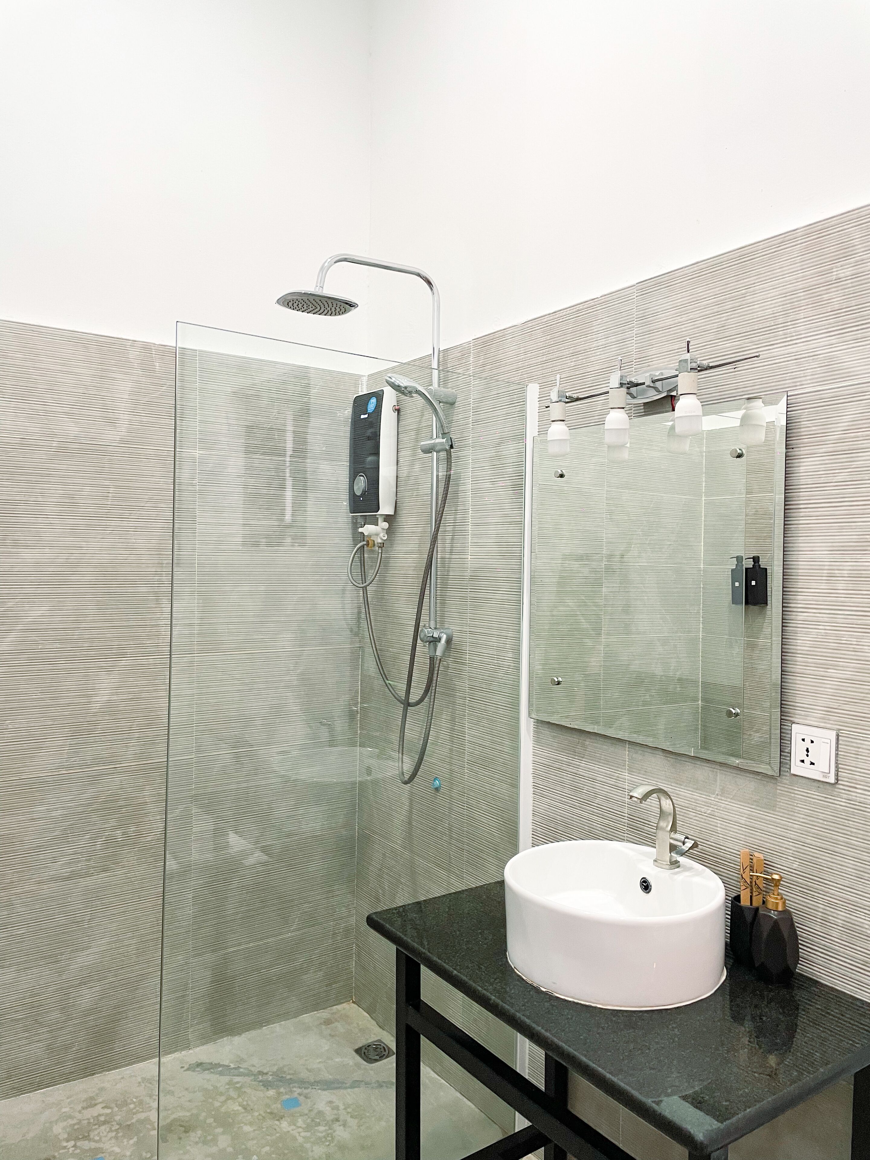 A modern bathroom with a glass-enclosed shower, a white sink, and a mirror above it.