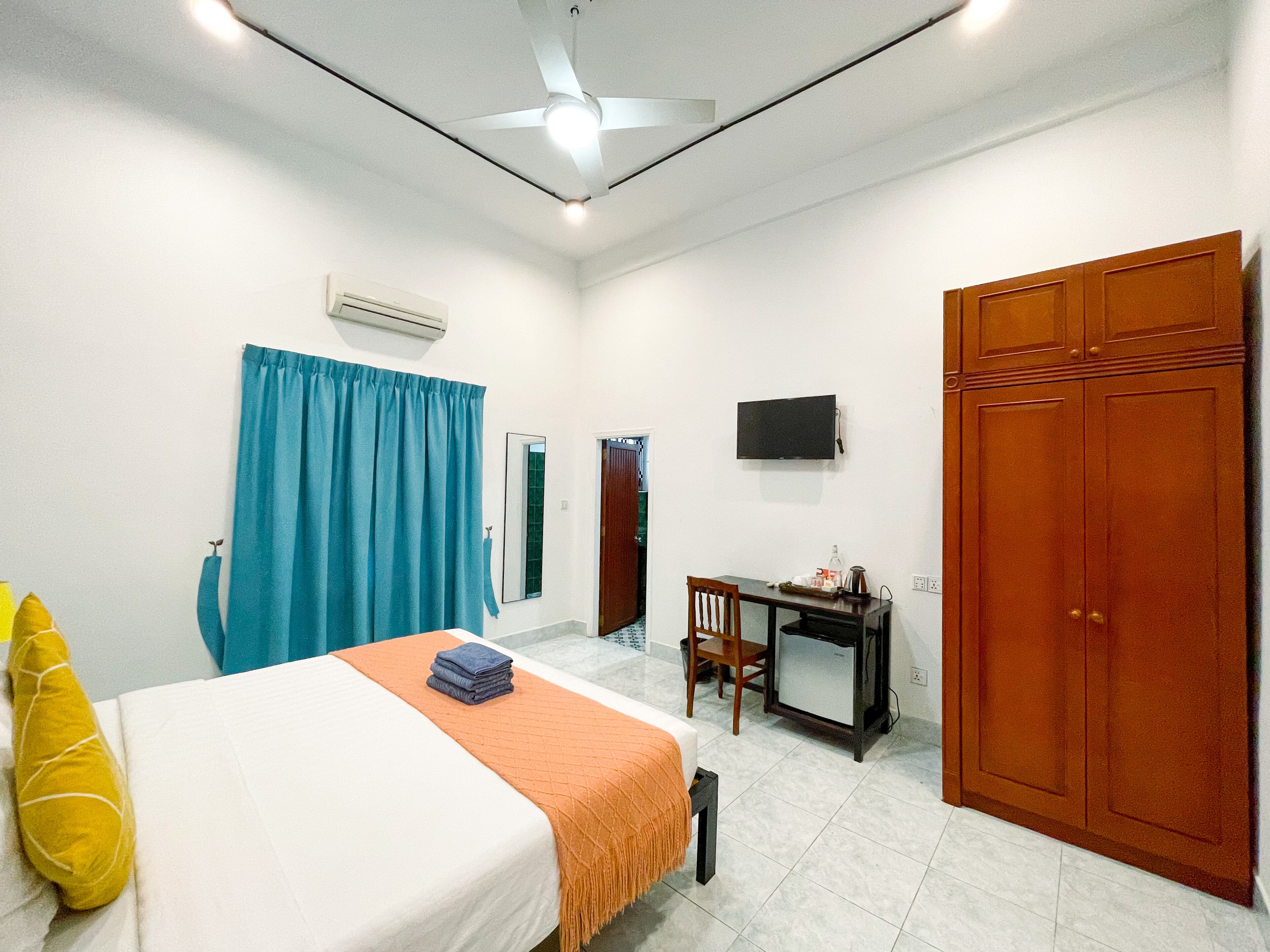 A hotel room with a bed, a desk, a television, and a wardrobe.