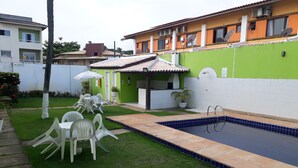A residential property with a swimming pool, a patio with chairs, and a green wall. - Village Duplex, 2 Bedrooms, 100m from the Beach with Pool (Salvador)