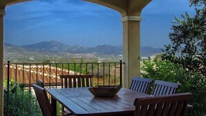 A covered outdoor seating area with a table and chairs, overlooking a mountainous landscape. - House / Villa - Budoni (Tanaunella (Budoni))