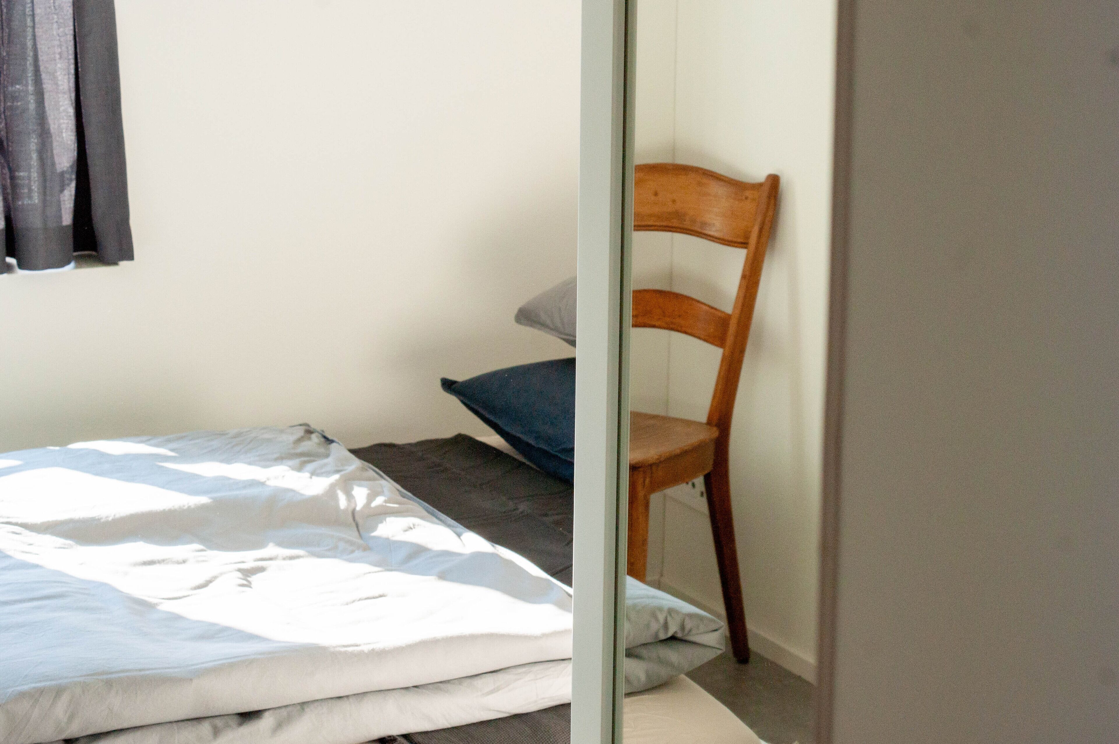 A bedroom with a bed, a chair, and a window with curtains.