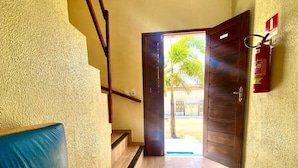 A hotel lobby with a blue sofa, a staircase, and a fire extinguisher on the wall. - Pousada Aguia da Vila (Jijoca de Jericoacoara)