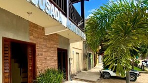 A hotel entrance with a sign reading "POUSADA," a covered walkway, and a parked vehicle. - Pousada Aguia da Vila (Jijoca de Jericoacoara)