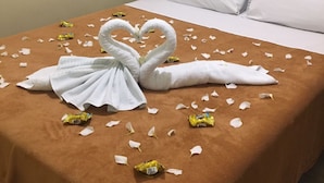 A hotel room with a bed covered in a brown blanket, white pillows, and a decorative swan made of towels on the bed. - Pousada Aguia da Vila (Jijoca de Jericoacoara)
