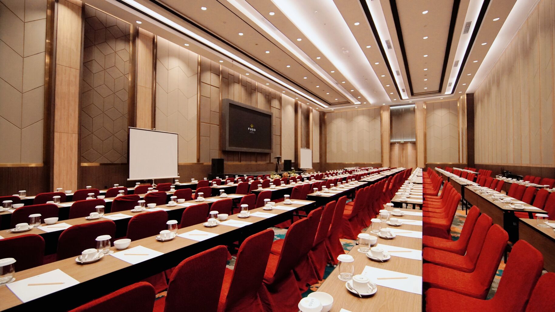 A conference room with long tables, red chairs, and a whiteboard.